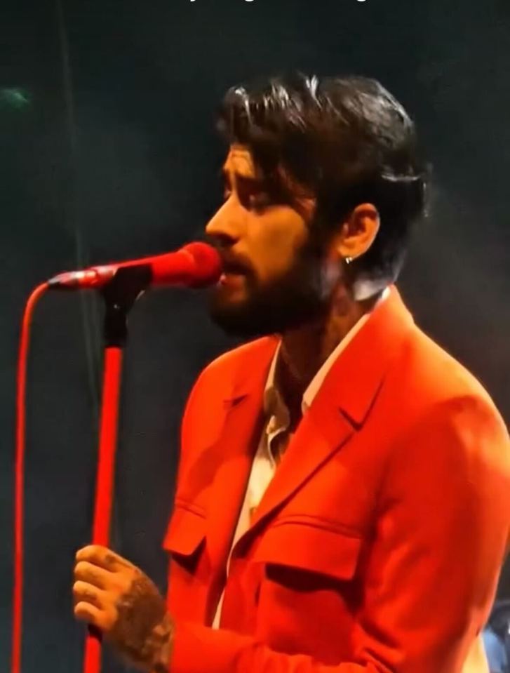Zayn Malik singing into a microphone.
