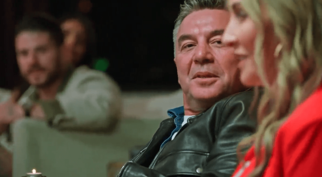A man and woman sitting together, the man wearing a leather jacket.
