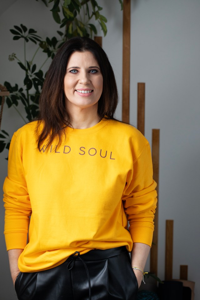 Portrait of a smiling woman wearing a yellow sweatshirt.