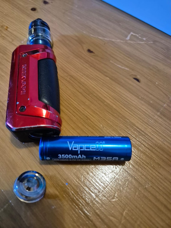 E-cigarette and battery components on a wooden surface.