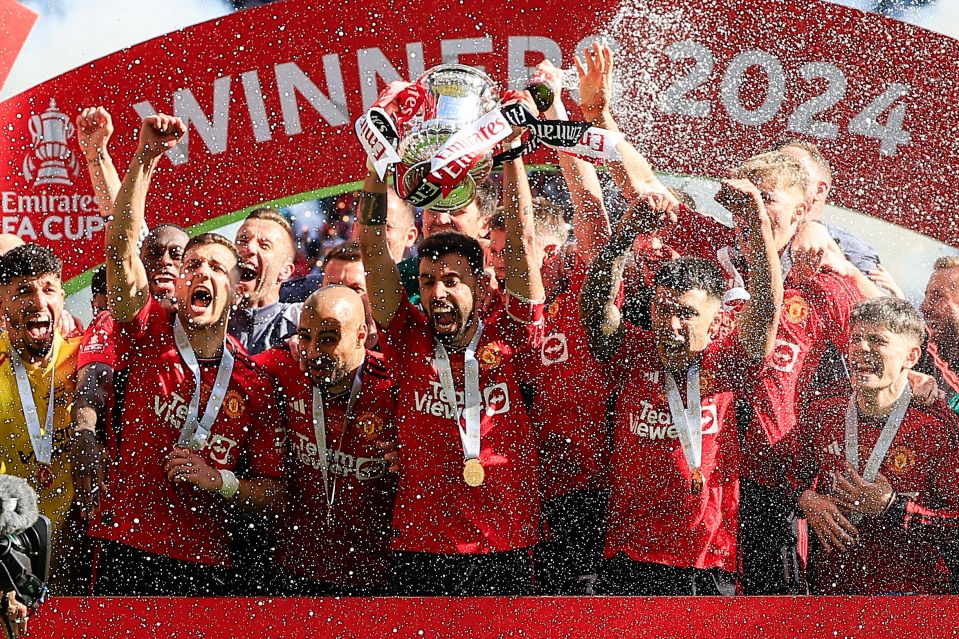 Manchester United players celebrating FA Cup victory, showered in champagne.