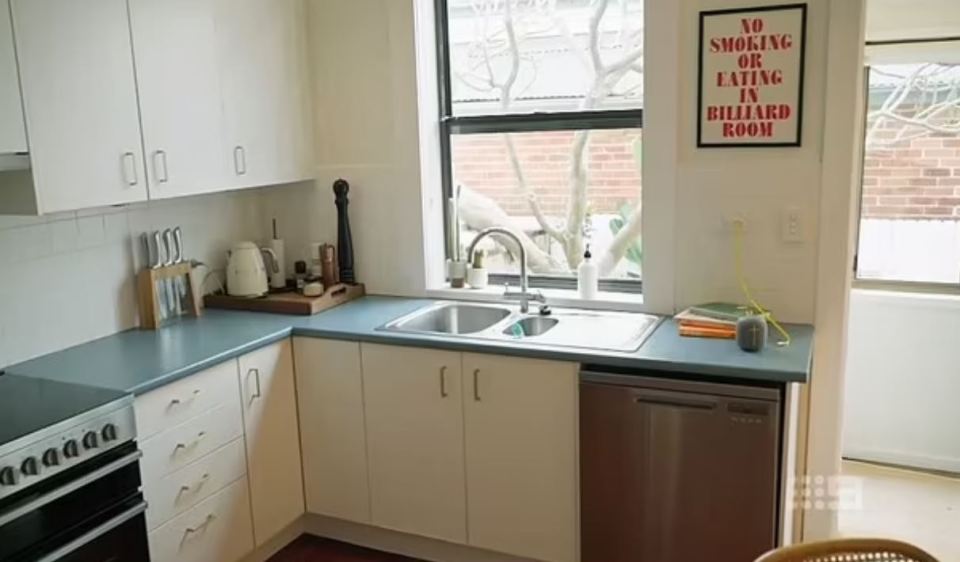 Kitchen with light-colored cabinets, a blue countertop, and a stainless steel dishwasher.