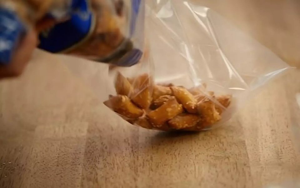Pretzels being poured into a plastic bag.