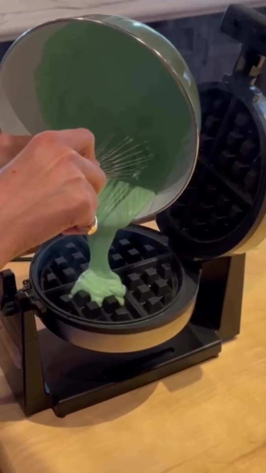 Green batter being poured into a waffle iron.