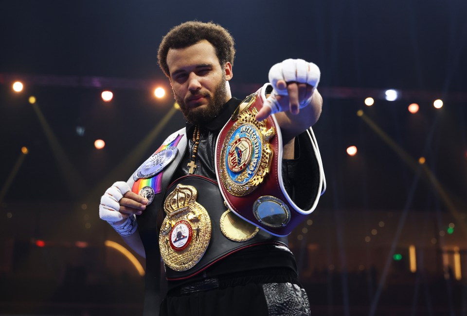 Moses Itauma celebrates a boxing victory with his championship belts.