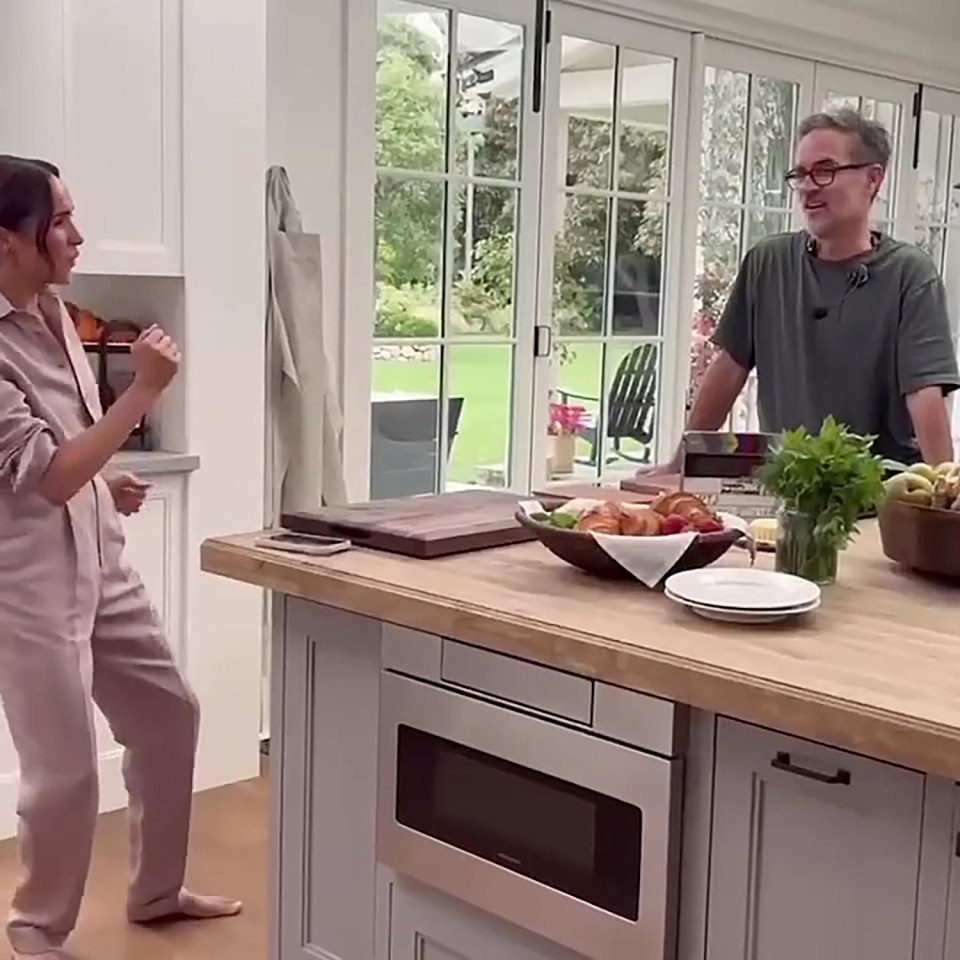 Meghan Markle and a crew member in a kitchen.