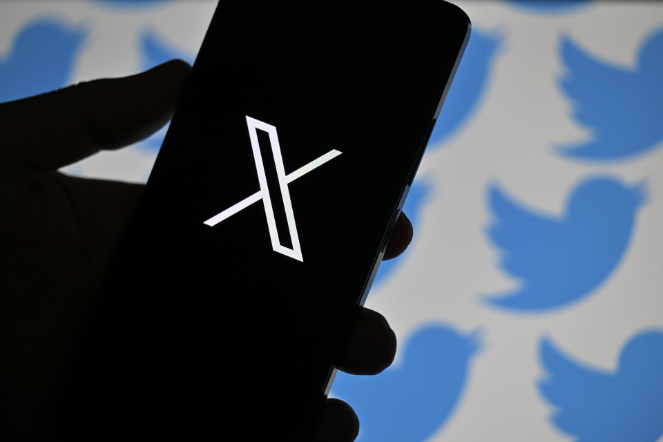 Phone displaying the new Twitter logo, X, with blurred Twitter bird logos in the background.
