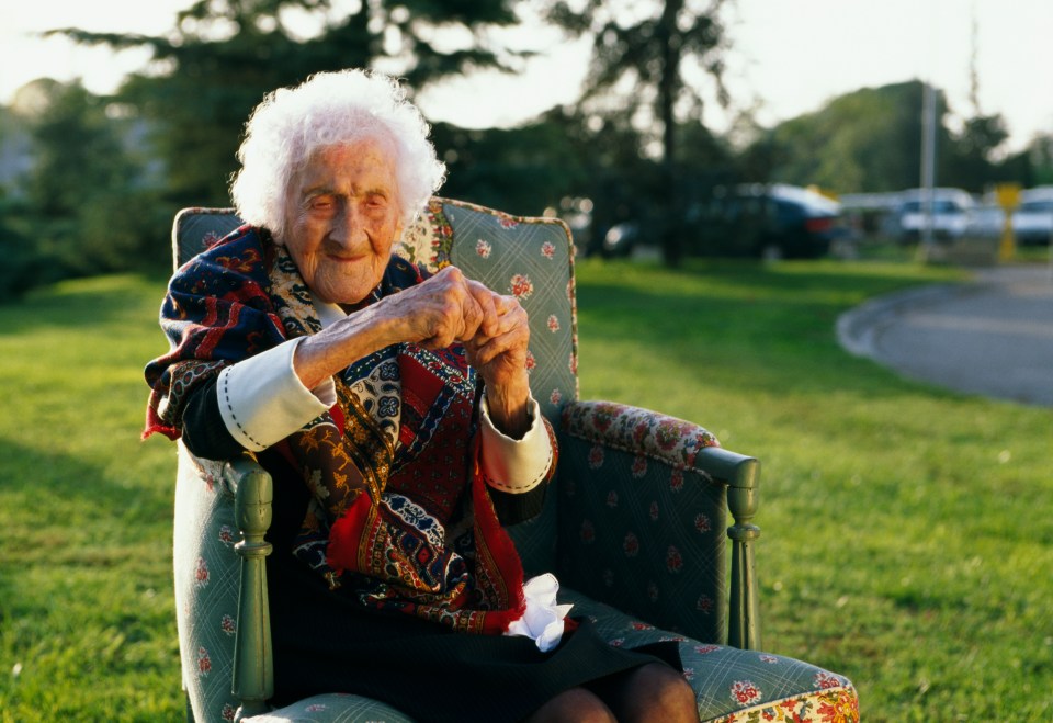 Jeanne Calment, the world's oldest person, sitting in a chair outdoors.