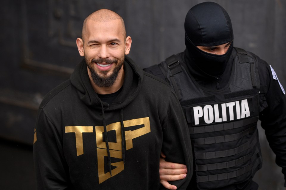 Andrew Tate escorted by a police officer.