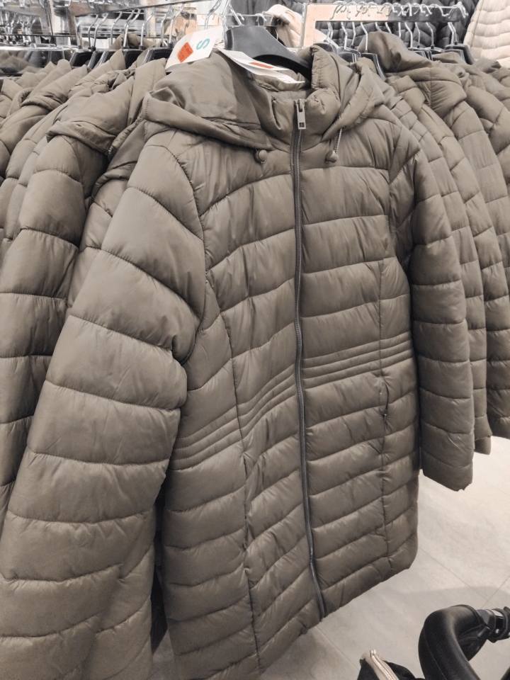 Several olive-green puffer jackets on hangers.