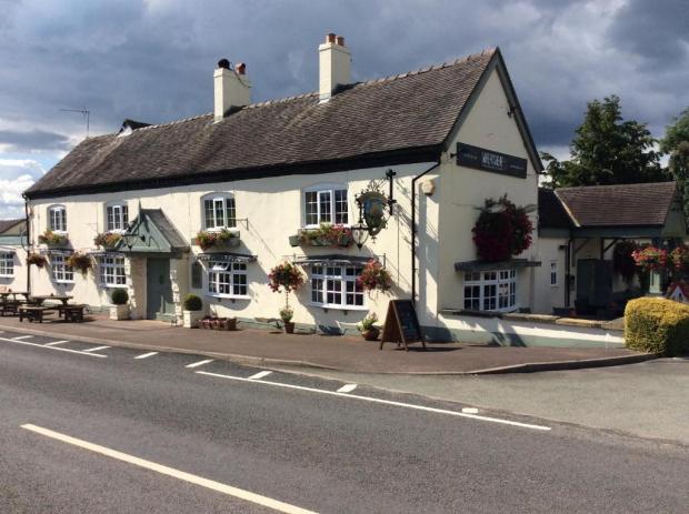 The Wheatsheaf Inn, a white pub with hanging flower baskets.