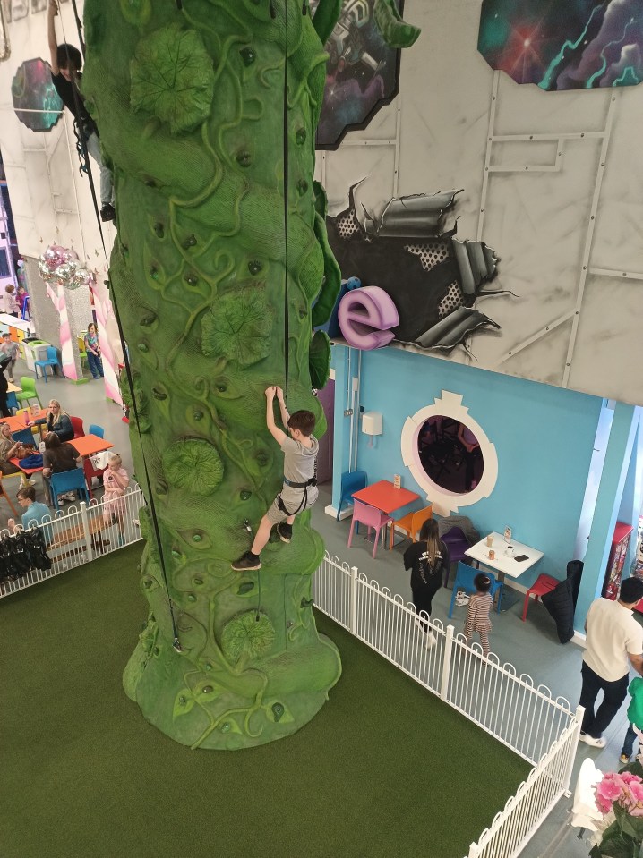 Boy climbing a green climbing wall at Riverside Hub in Northampton.