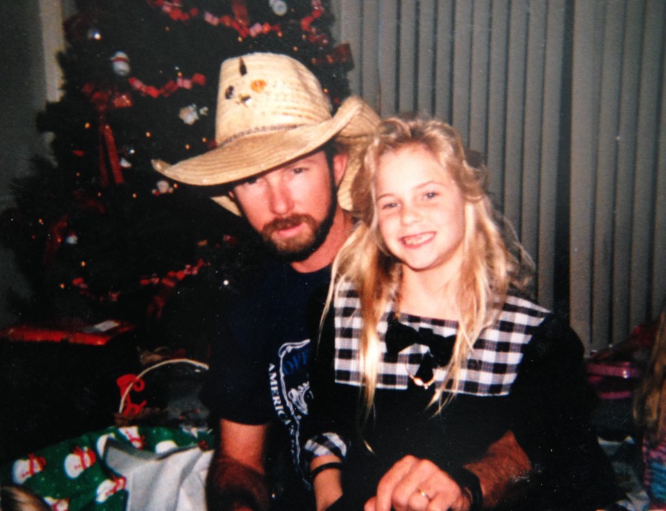 Photo of a father and daughter near a Christmas tree.