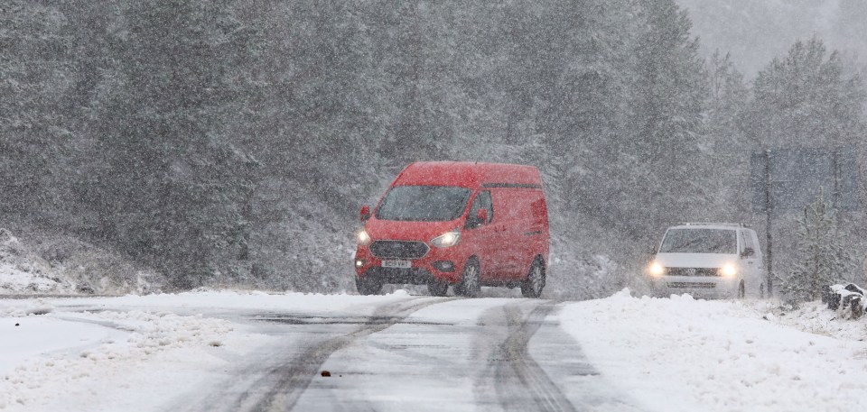 Vehicles driving on a snow-covered road during a blizzard.