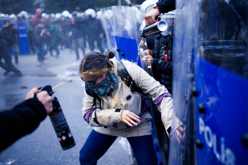 Riot police using pepper spray on a protester.