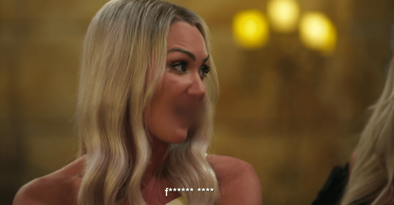 Screenshot of a blonde woman reacting to being called a vulgar insult by her sister at a wedding.