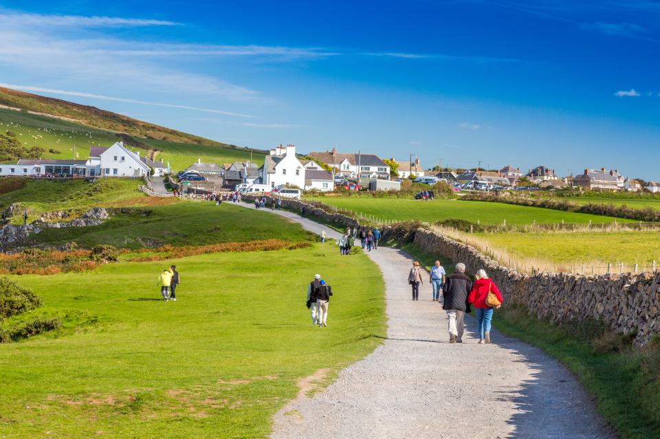 People walking on a path toward Rhossili village in Wales.