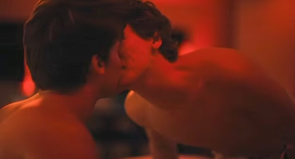 Screenshot of a scene from White Lotus showing two men kissing.