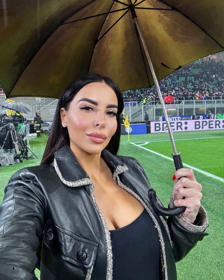 Woman under umbrella at a soccer game.