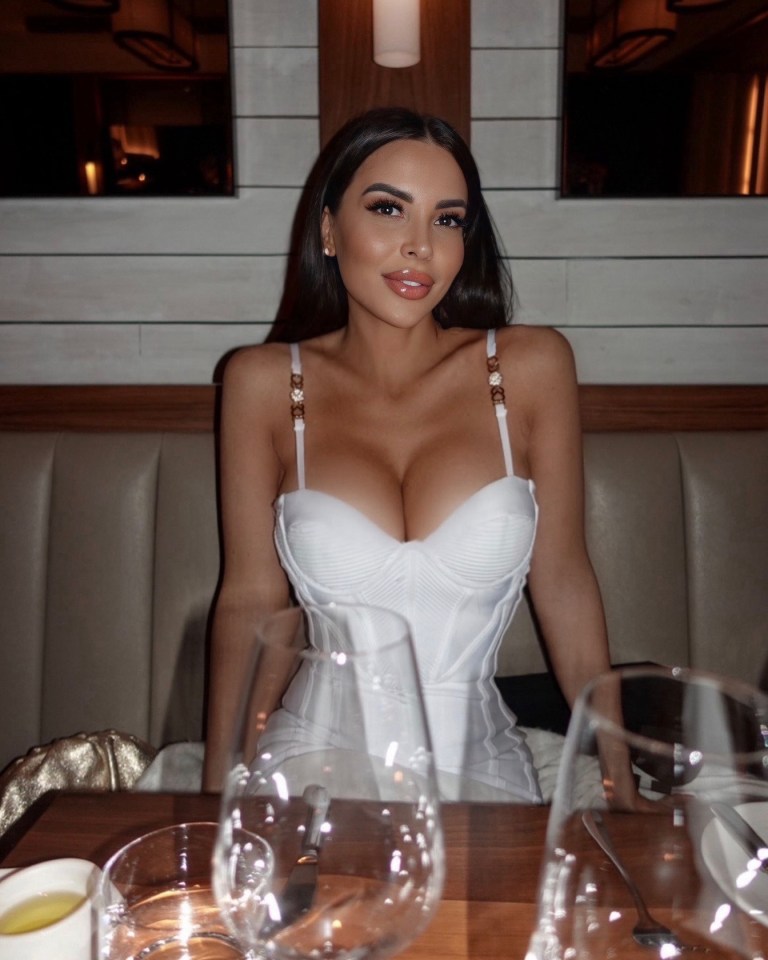 Woman in white corset dress at restaurant table.