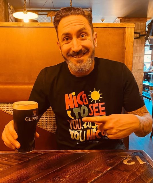 Man in a "Nice to see you, you nice" t-shirt holding a pint of Guinness.