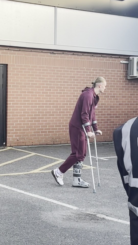 Man on crutches leaving a stadium.