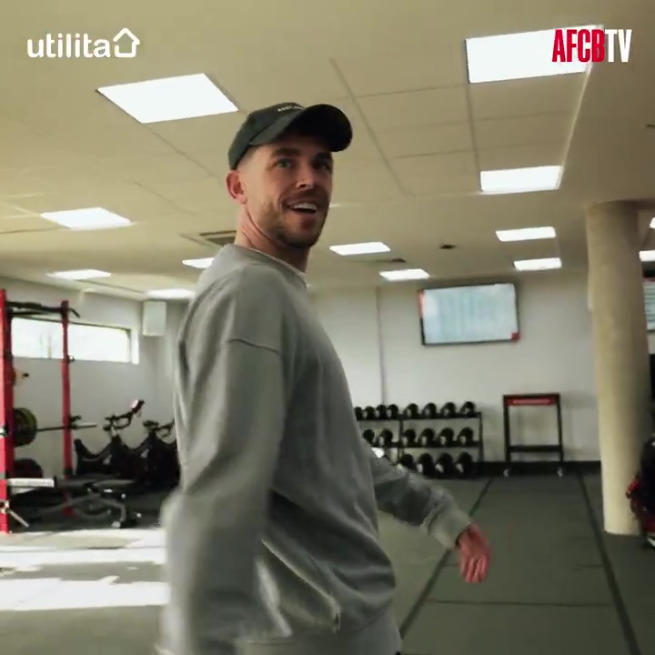 Man in gray sweatshirt walking through gym.
