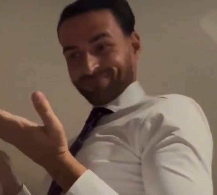 Man in a white shirt making a gesture.