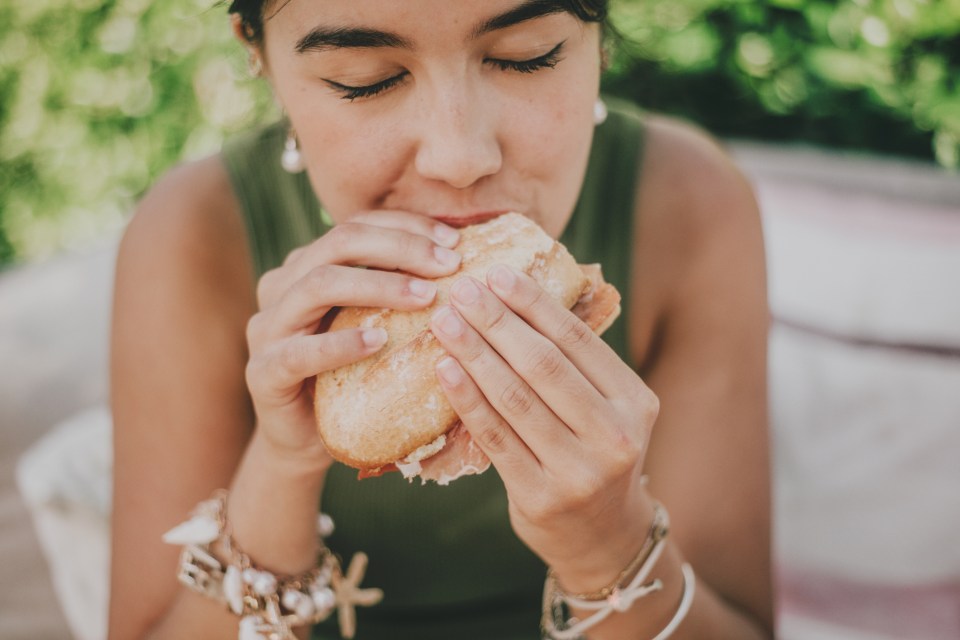 Woman eating a ham sandwich.