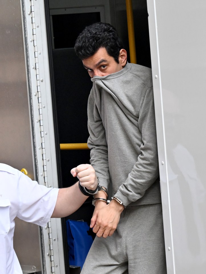 A handcuffed man in a grey sweatshirt partially obscuring his face.