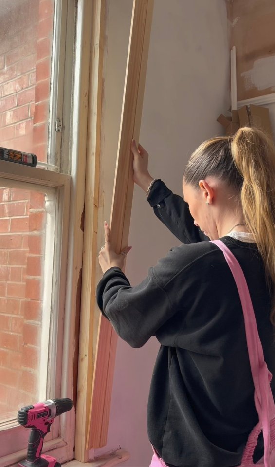 Woman installing window trim.