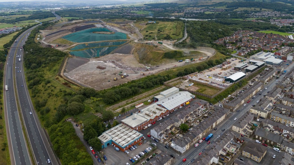 Aerial view of a landfill site near a town and highway.