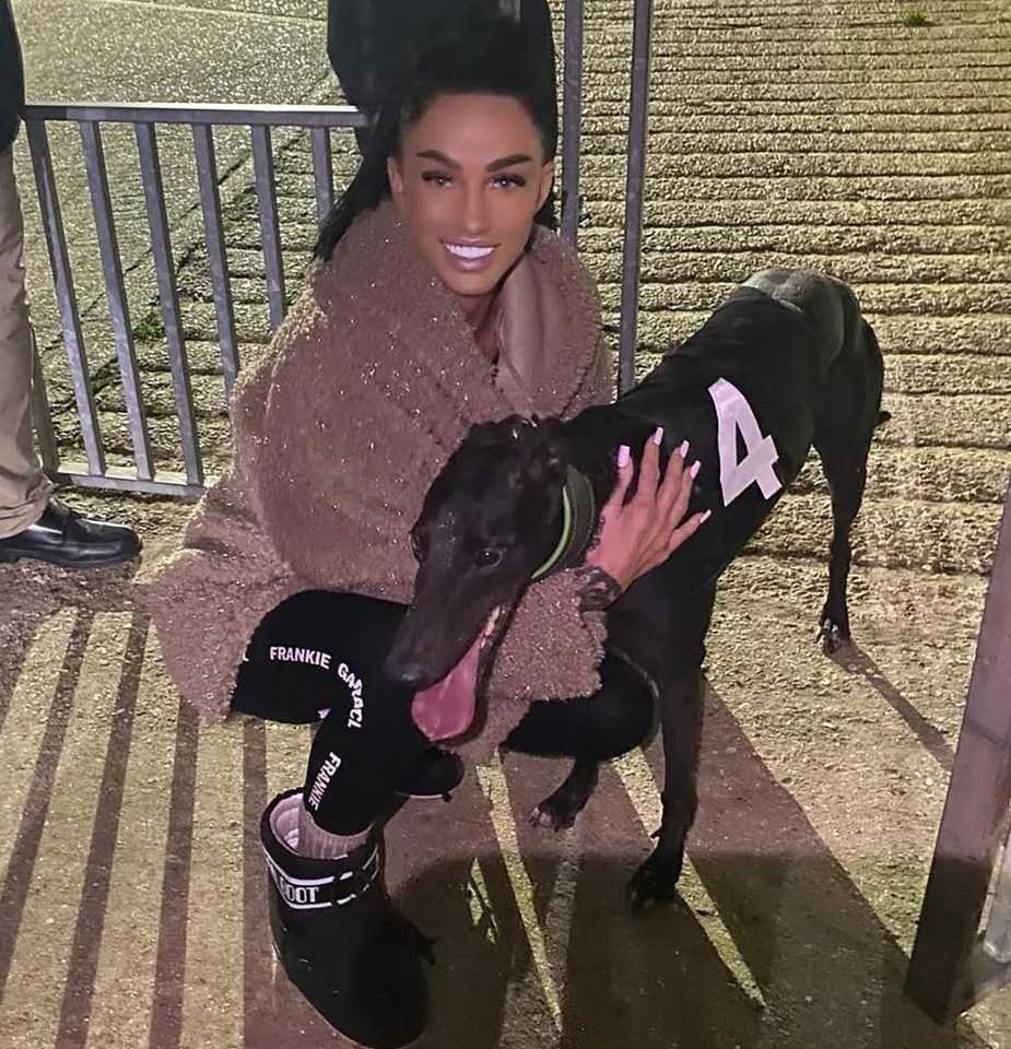 Woman posing with a racing greyhound wearing number 4.