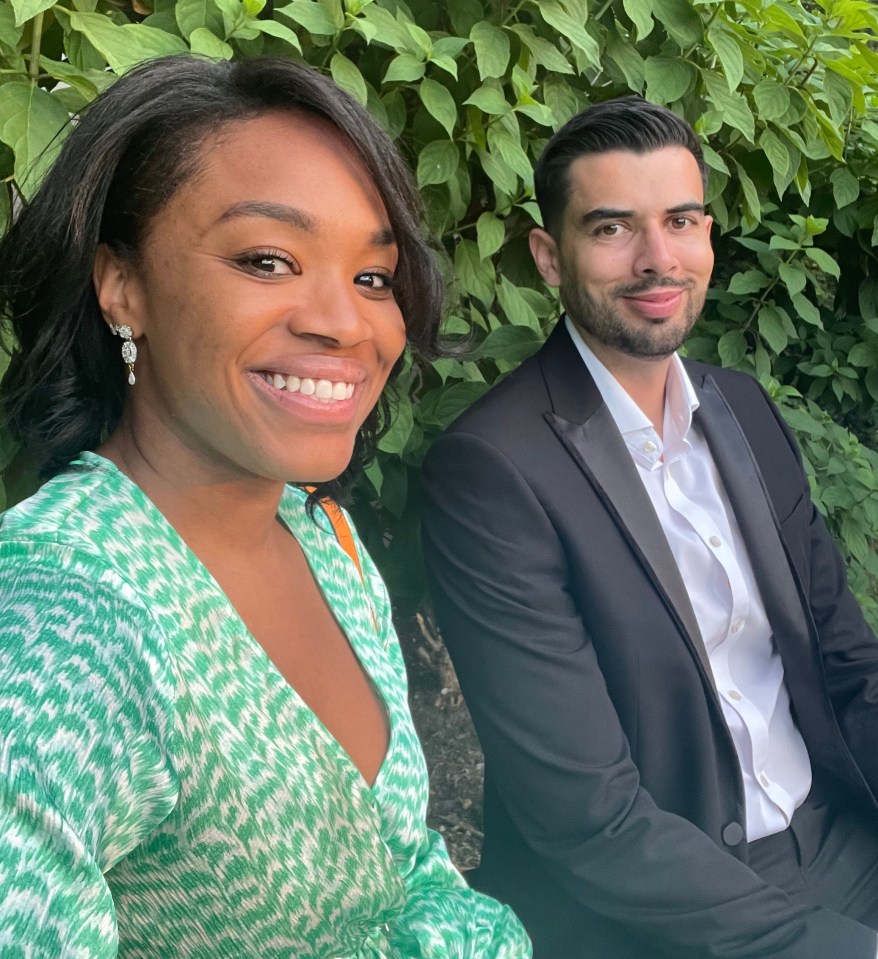 A woman in a green dress and a man in a black tuxedo sitting together outdoors.