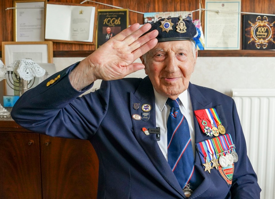 A veteran saluting, wearing a navy blue blazer with medals and badges.
