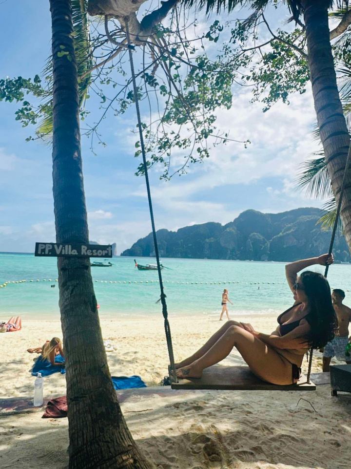 Woman sitting on a swing at PP Villa Resort beach.