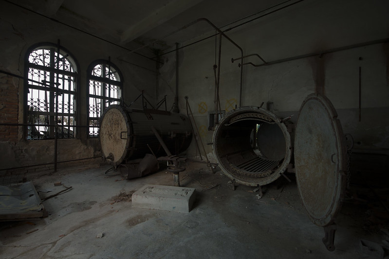 Interior of Poveglia Psychiatric Hospital in Venice, showing two large, rusty autoclaves.