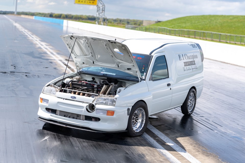 A modified Ford Escort van on a drag strip, hood open, showing its engine.