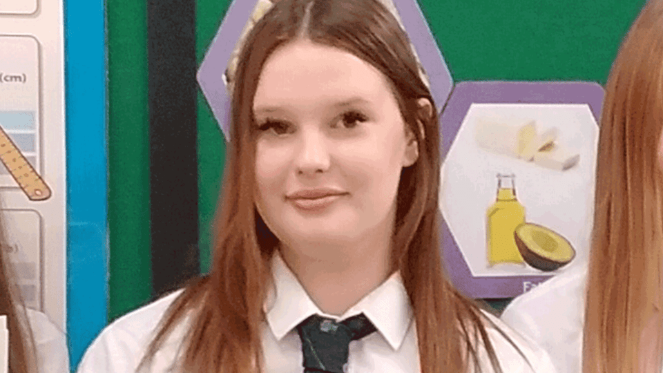 Teenage girl in school uniform smiling.