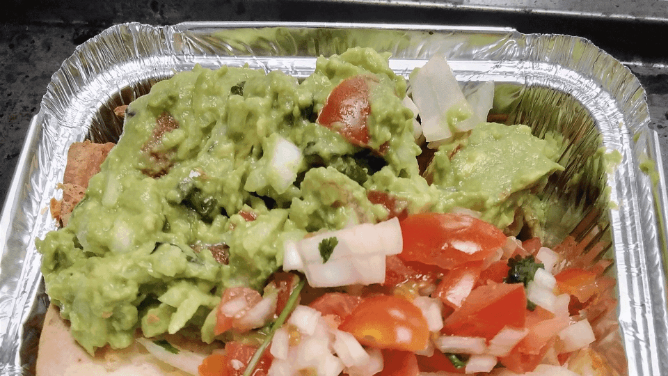 Guacamole and pico de gallo in a foil container.