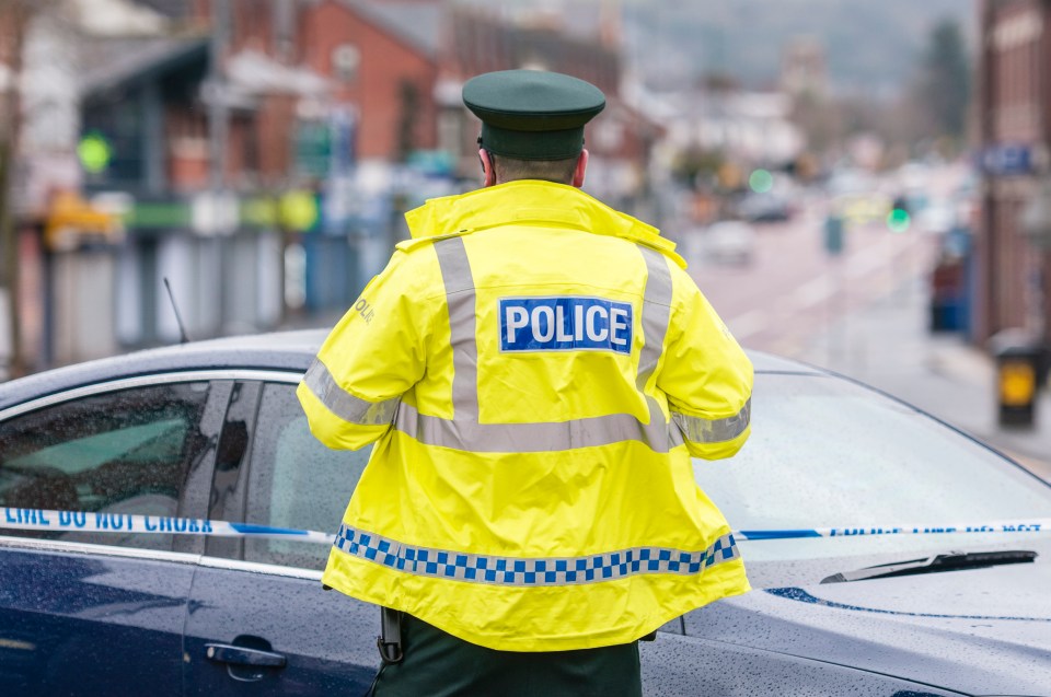 Police officer in high-visibility jacket at a crime scene.