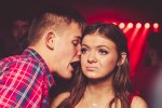 Woman looking unimpressed while a man whispers in her ear.