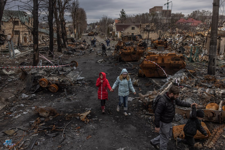 A family walks past destroyed Russian military machinery in Bucha, Ukraine.