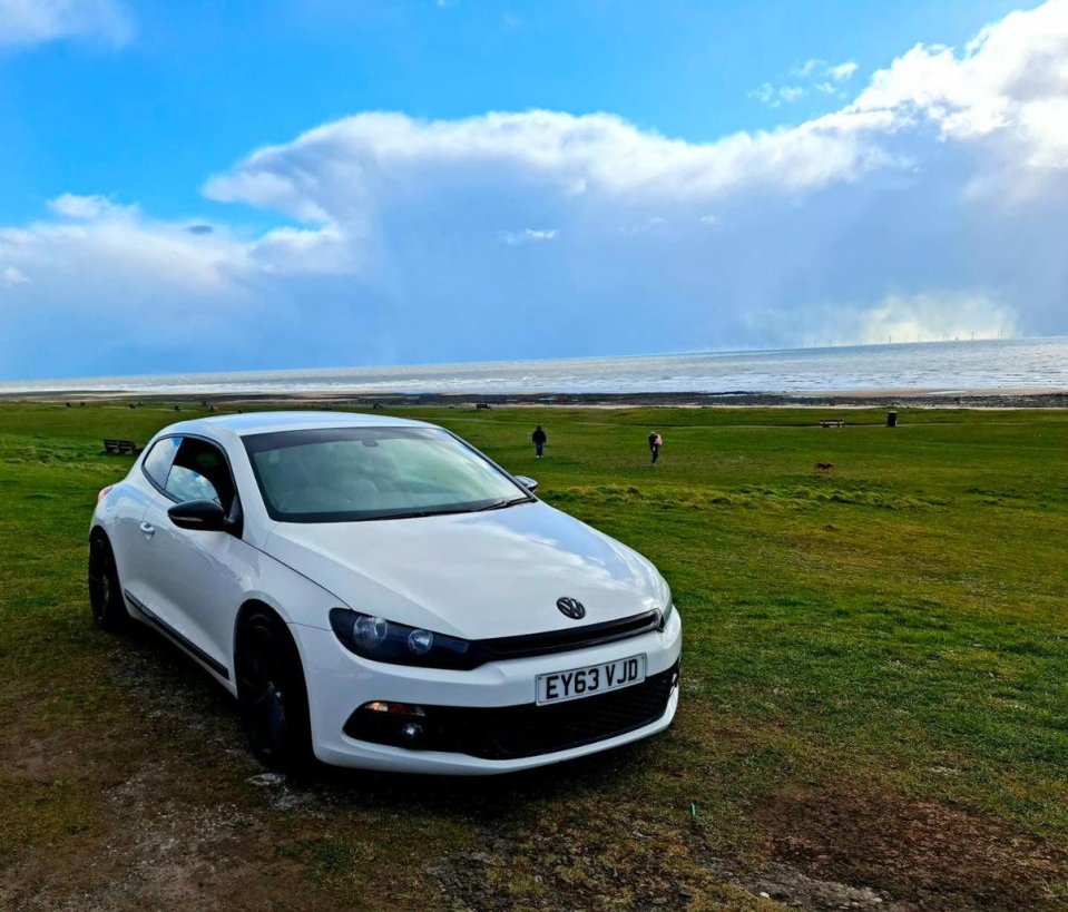 White Volkswagen Scirocco parked near the ocean.