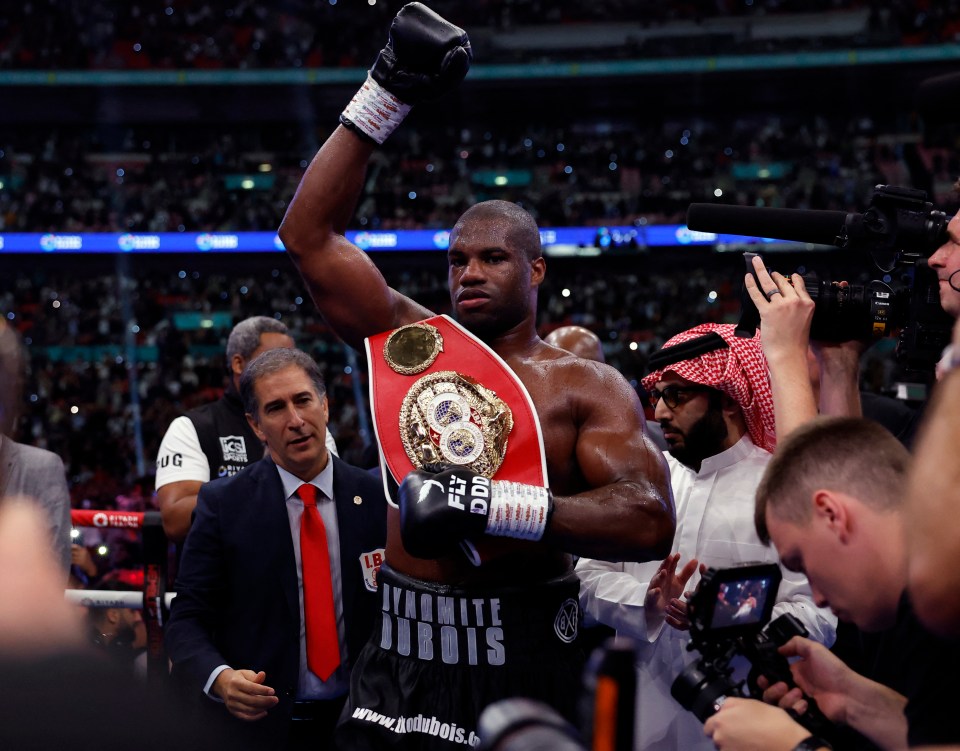 Daniel Dubois celebrates a boxing victory, holding up his championship belt.