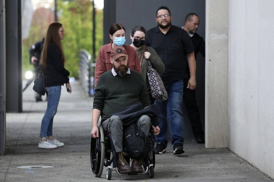 People leaving a courthouse, one person in a wheelchair.