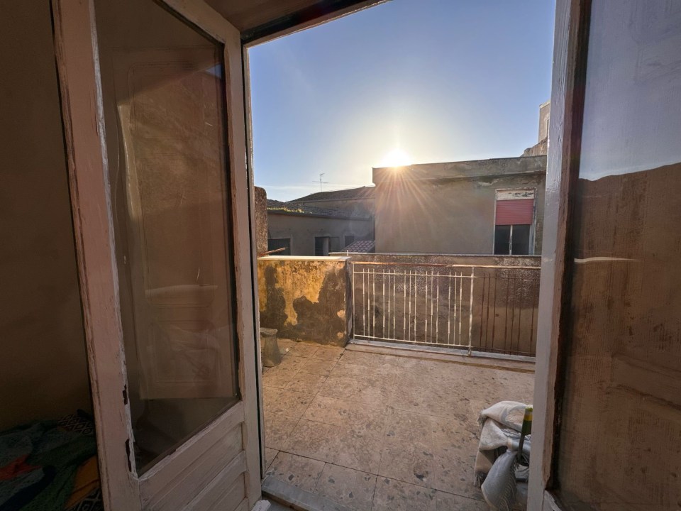 View from a doorway of a sunlit patio and surrounding buildings.