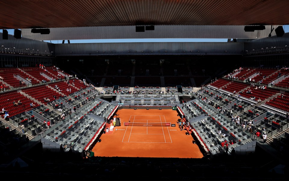 Empty tennis court with spectators in stands.