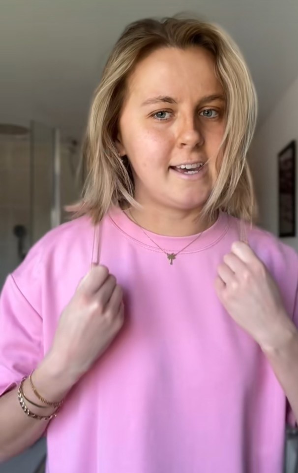 Woman in pink sweatshirt talking to camera.