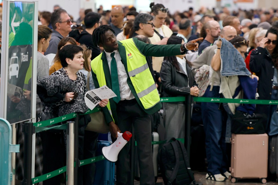 A worker directs passengers waiting at a train station due to a power outage.